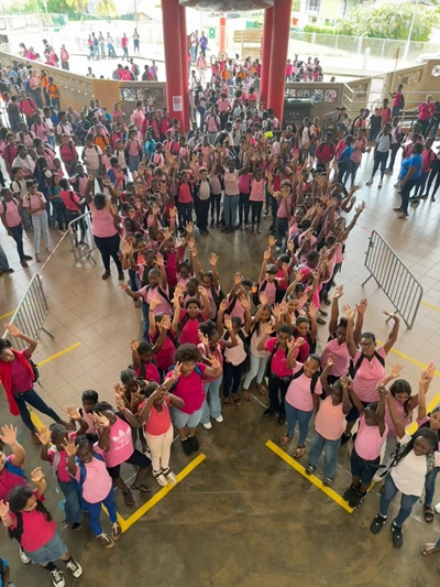 Les élèves vêtus de rose rassemblés sous le préau pour le ruban humain, bras levés