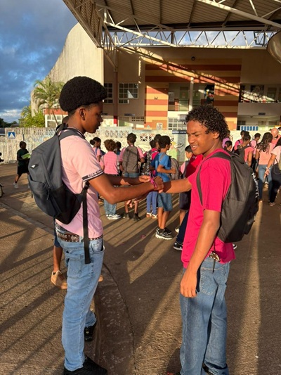 Un élève attache un ruban rose au poignet d'un camarade