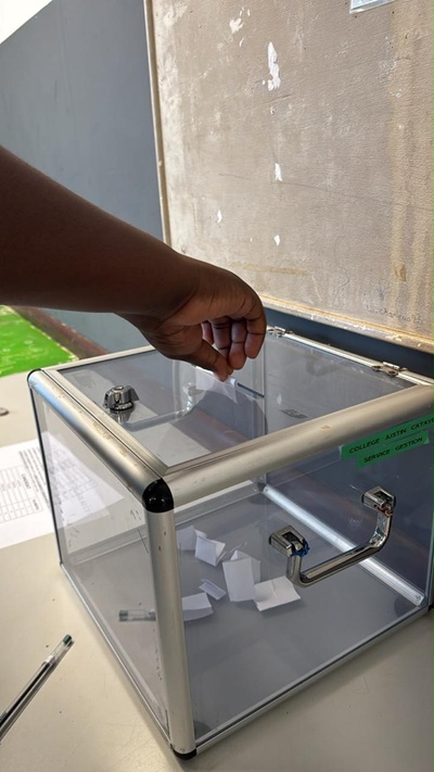 Un élève penché sur l'urne pour voter